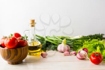 Olive oil, garlic and tomato on the white wooden background. Vegetarian  vegan food background. Healthy eating concept with fresh vegetables. Copy space.