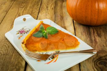Thanksgiving pumpkin pie slice, mint on a wooden background