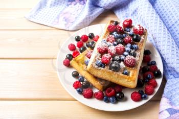 Soft waffle with blueberry and raspberry on blue linen napkin. Breakfast soft waffles with fresh berries