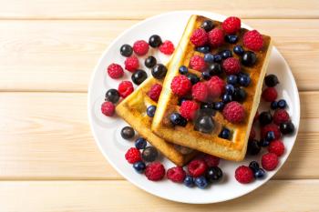 Soft waffle with fresh blueberry and raspberry top view. Breakfast soft waffles with fresh seasonal berries