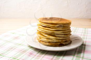 Stack of breakfast pancakes on the white plate. Homemade pancakes served for breakfast.