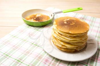 Stack of homemade breakfast pancakes and green pan. Homemade pancakes served for breakfast.