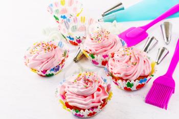 Swirl cupcake with whipped cream frosting and confectionery syringe. Birthday cupcake with pink whipped cream. Homemade decorated cupcakes. 