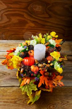 Thanksgiving  centerpiece with candle and artificial fall leaves vertical. Thanksgiving greeting with fall decor. Fall decoration. 