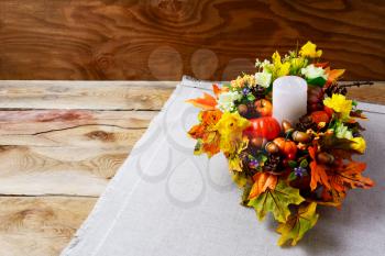Thanksgiving  centerpiece with candle and artificial fall leaves. Thanksgiving background with fall decor. Fall background. Copy space.