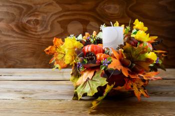 Thanksgiving decoration with white candle and silk fall leaves . Thanksgiving background with fall decor. Fall background. Copy space.