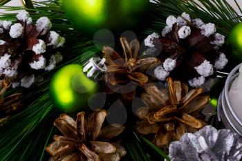 Christmas background with snowy pinecone and green ornaments. Christmas party decoration with shiny balls.