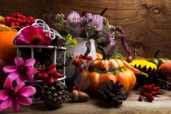 Thanksgiving arrangement with turban squash, rowan berries, clower, white birdcage, pine cones, pink and purple flowers