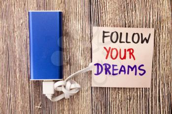 Follow your dreams motivational handwritten message on white paper above retro wooden background. Concept with positive motivation words on the retro backgrounds.