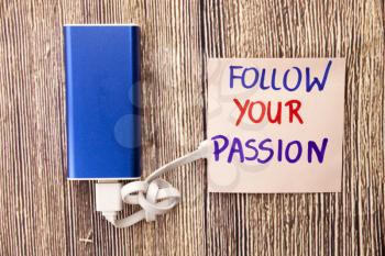 Follow your Passion is shown on note paper in various colors. power device of blue color with white cable on wooden background. This photo is about motivational Concept to himself.