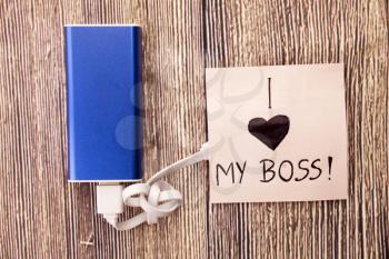 Power Bank with a piece of paper around, having words I Love my boss is present.Love for an officer, head or boss is mentioned in image. Business Concept is shown in picture.