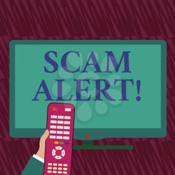 Text sign showing Scam Alert. Business photo showcasing illegal trick usually with purpose of getting money from showing Hand Holding Computer Remote Control infront of Blank Wide Color PC Screen