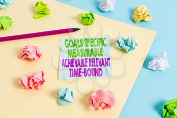 Handwriting text Goals Specif Measureable AC. Conceptual photo Goals Specific Measurable Achievable Relevant Time Bound Colored crumpled papers empty reminder blue yellow background clothespin