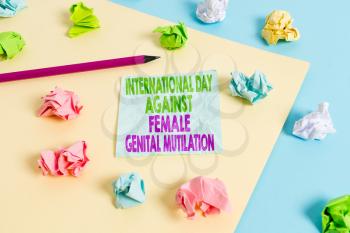 Handwriting text International Day Against. Conceptual photo International Day Against Female Genital Mutilation Colored crumpled papers empty reminder blue yellow background clothespin