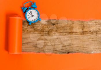Alarm clock and torn cardboard placed above a wooden classic table backdrop