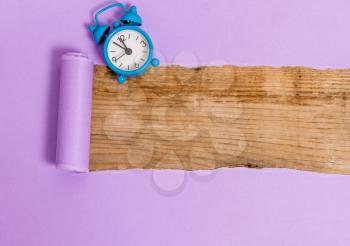 Alarm clock and torn cardboard placed above a wooden classic table backdrop