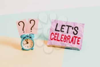 Handwriting text Let S Celebrate. Conceptual photo party or other social event on a special day or occasion Mini size alarm clock beside a Paper sheet placed tilted on pastel backdrop