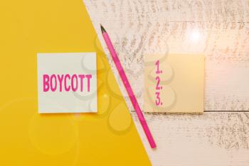 Conceptual hand writing showing Boycott. Concept meaning stop buying or using the goods or services of a certain company Blank notepads pen colored paper sheet wooden background