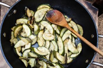 Preparation of zucchini in frying pan with hot oil. Delicious vegetables sliced and fried in oil. Sliced courgette and prepared in hot oil. Vegetarian food fried in frying pan.