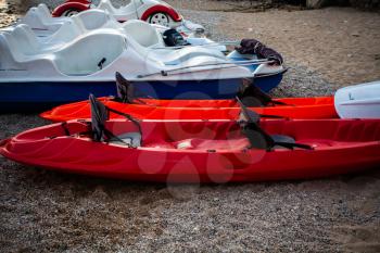 Red and white kayaks on sand. Boats for leisure sailing laying on the beach. Kayak adventure trip. Extreme sports. Relaxing time. Enjoying life. Summer vacation 