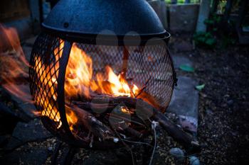 Closeup view on open fire flames. Burning bonfire in the metal housing heater. Campfire in motion image. Frozen image of blaze. Dark mood photo with charring