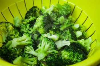 Healthy food concept with green broccoli vegetables. Top view of plastic bowl with vegetables. Full bowl of broccoli in closeup view. Fresh and clean vegetables.