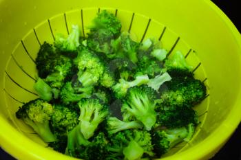 Full bowl of broccoli in closeup view. Fresh and clean vegetables. Healthy food concept with green broccoli vegetables. Top view of plastic bowl with broccoli.