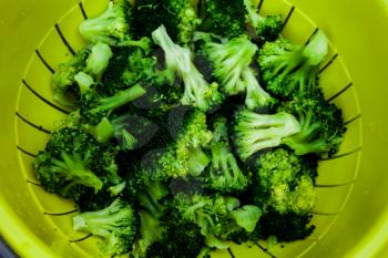 Healthy food concept with green broccoli vegetables. Top view of plastic bowl with vegetables. Full bowl of broccoli in closeup view. Fresh and clean vegetables.