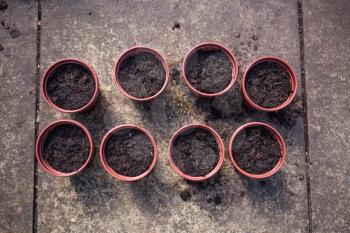 Top view of flower pots filled with soil. Preparing plastic pots for gardening. Concept with soil and gardening pots. Seeding plants in the flower pots