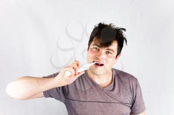Health and beauty concept image with brushing teeth. Joyful young man smiling during morning hygiene. Close-up of young man brushing teeth with electric toothbrush.
