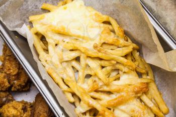 Flat lay above served fast food. French fries in the paper box. Fried potatoes with melted cheese on the top. Unhealthy fast food meals. Delicious meal prepared with cheese