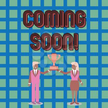 Text sign showing Coming Soon. Business photo text event or action that will happen after really short time Man and Woman in Business Suit Holding Together the Championship Trophy Cup
