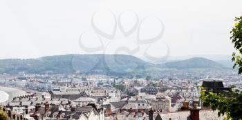 City of Llandudno in North Wales, United Kingdom. Traditional UK cityscape from the hilltop. Town aerial view over busy main street and houses. Photo of british houses' roofs and chimneys