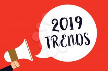 Handwriting text 2019 Trends. Concept meaning things that is famous for short period of time in current year Man holding megaphone loudspeaker speech bubble screaming red background