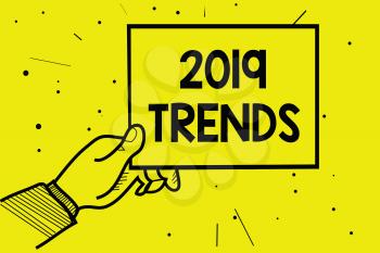 Word writing text 2019 Trends. Business concept for things that is famous for short period of time in current year Man hand holding paper communicating information dotted yellow background