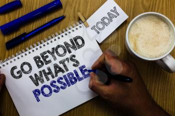Text sign showing Go Beyond What s is Possible. Conceptual photo do bigger things You can reach dreams Man holding marker notebook clothespin reminder wooden table cup coffee