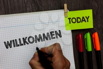 Conceptual hand writing showing Willkommen. Business photo text welcoming people event or your home something to that effect Man holding marker notebook clothespin markers wooden table