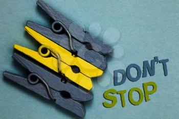 Conceptual hand writing showing Don t not Stop. Business photo text Continue what had been doing without rendering a delay Gray yellow vintage clothespins clear background Holding things
