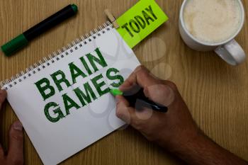 Conceptual hand writing showing Brain Games. Business photo showcasing psychological tactic to manipulate or intimidate with opponent Man holding marker notebook reminder wooden table cup coffee