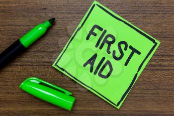 Conceptual hand writing showing First Aid. Business photo showcasing Practise of healing small cuts that no need for medical training Green Paper Communicate ideas Marker Wooden background