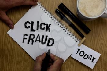 Writing note showing Click Fraud. Business photo showcasing practice of repeatedly clicking on advertisement hosted website Man holding marker notebook clothepin reminder wooden table cup coffee