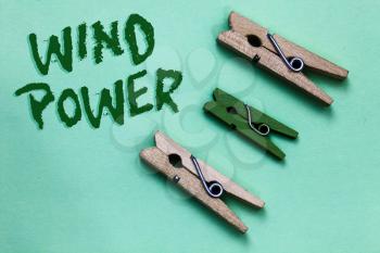 Text sign showing Wind Power. Conceptual photo use of air flowto provide mechanical power to turn generators Three brown green vintage clothespins clear background Holding things
