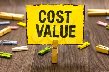 Text sign showing Cost Value. Conceptual photo The amount that usualy paid for a item you buy or hiring a person Clothespin holding yellow paper note several clothespins wooden floor