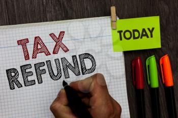 Conceptual hand writing showing Tax Refund. Business photo text applied when money liability is less than the paid ones Man holding marker notebook clothespin markers wooden table
