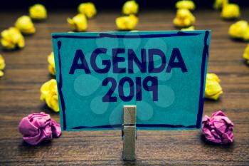 Text sign showing Agenda 2019. Conceptual photo list of activities in order which they are to be taken up Clothespin holding blue paper note crumpled papers several tries mistakes