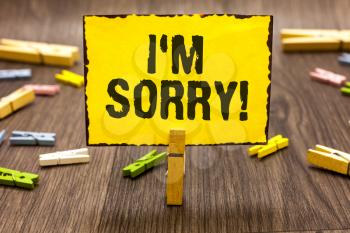 Text sign showing I am Sorry. Conceptual photo To ask for forgiveness to someone you unintensionaly hurt Clothespin holding yellow paper note several clothespins wooden floor