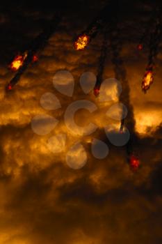 Grunge fireballs with smoke tails over cloudy background.