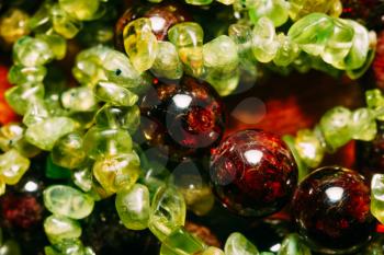 Dark red beads of garnet and olive green peridot gravel, natural stone close up.