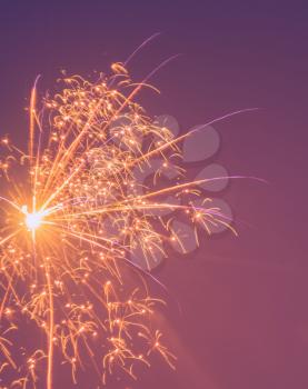 Photo of fireworks in purple and orange colour background.