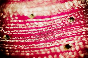 Textile of pink color decorated with strasses, bokeh effect, textured with paper.